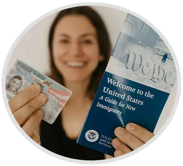 Smiling woman holding her new Permanent Resident Card and the USCIS Welcome to the United States guide after a successful Green Card renewal